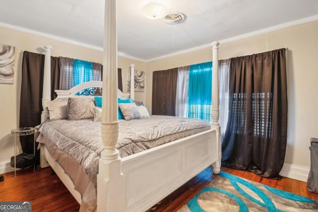 bedroom featuring ornamental molding, visible vents, baseboards, and wood finished floors