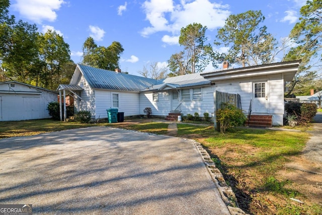 view of front of property featuring entry steps, metal roof, a chimney, and an outdoor structure