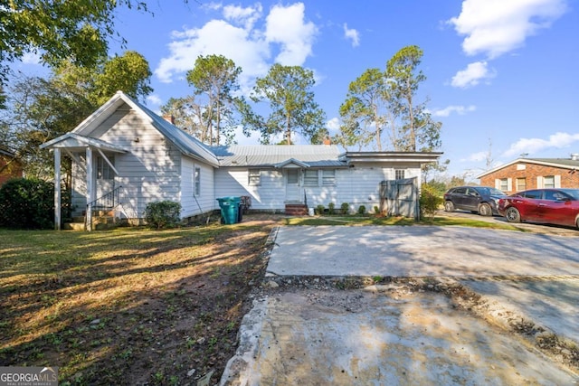 view of front of house featuring metal roof, driveway, and a front yard