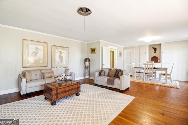 living area with baseboards, wood finished floors, visible vents, and crown molding