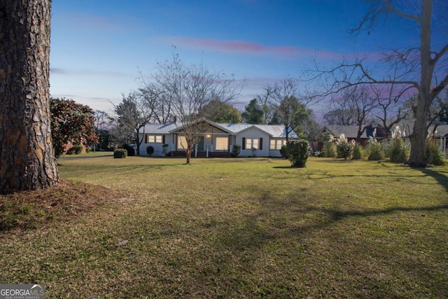 view of front of property with metal roof and a yard