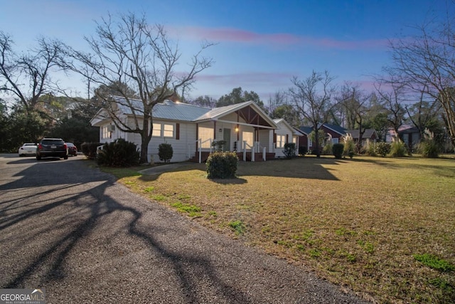 single story home featuring covered porch, metal roof, and a front lawn