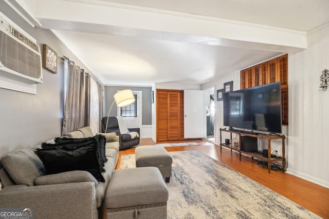 living area with a wall unit AC and wood finished floors