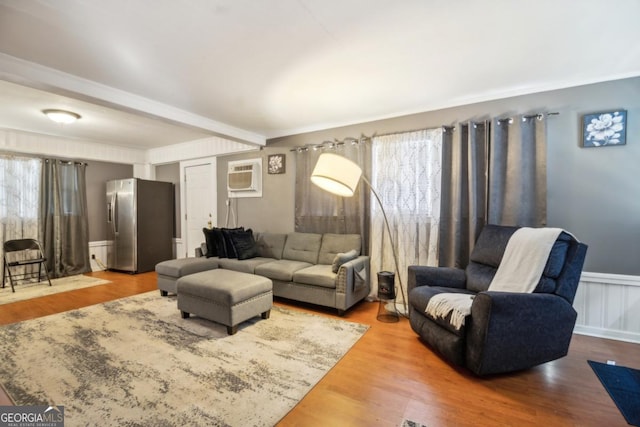 living room featuring a wainscoted wall, a wall mounted AC, wood finished floors, and a healthy amount of sunlight