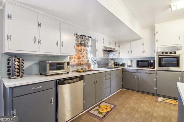 kitchen featuring under cabinet range hood, appliances with stainless steel finishes, a toaster, and gray cabinetry