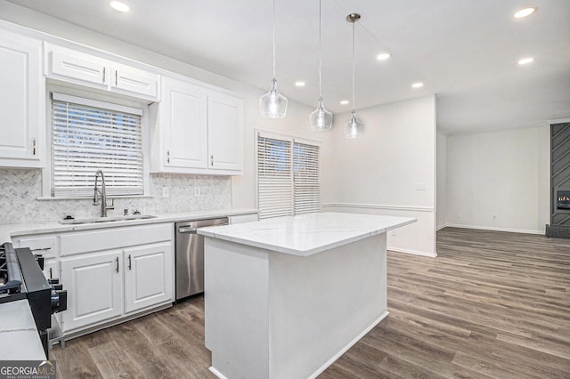 kitchen with stainless steel appliances, dark wood-style flooring, a sink, white cabinets, and backsplash