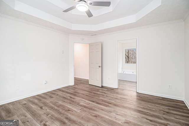 1320 Kay Ter SE, Conyers, GA 30013 - unfurnished bedroom with baseboards, a raised ceiling, ensuite bathroom, and wood finished floors