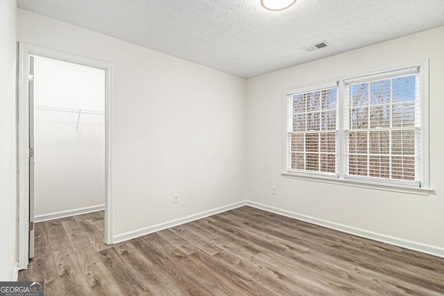 1320 Kay Ter SE, Conyers, GA 30013 - unfurnished bedroom featuring a closet, wood finished floors, a textured ceiling, a walk in closet, and baseboards
