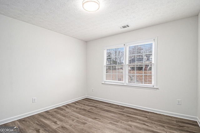 1320 Kay Ter SE, Conyers, GA 30013 - spare room featuring a textured ceiling, visible vents, baseboards, and dark wood-style floors