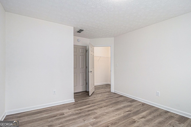 1320 Kay Ter SE, Conyers, GA 30013 - unfurnished bedroom featuring a closet, a textured ceiling, baseboards, visible vents, and wood finished floors