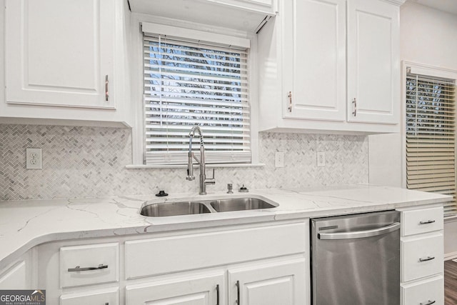 kitchen with tasteful backsplash, stainless steel dishwasher, a sink, and white cabinets