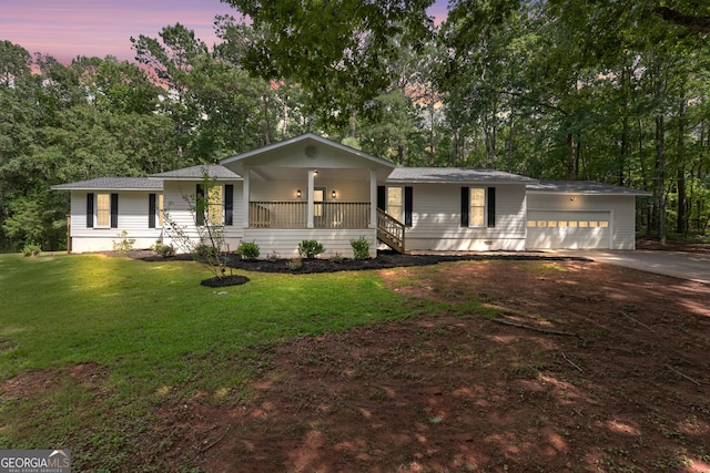 single story home with covered porch, a yard, an attached garage, and driveway