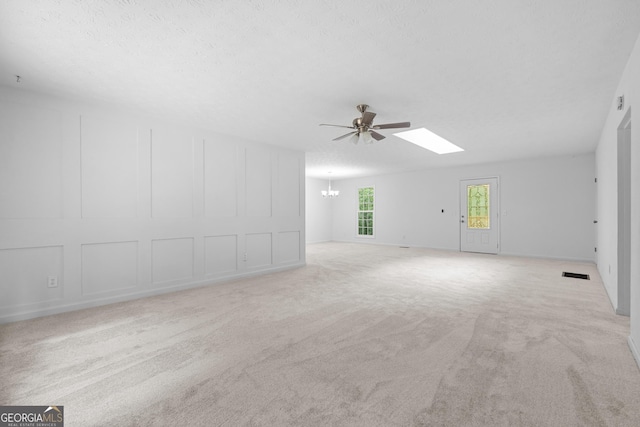 interior space with a skylight, light carpet, a decorative wall, and visible vents