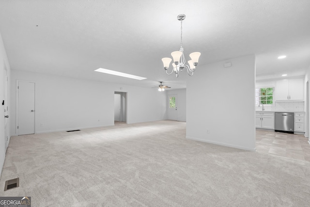 empty room featuring a healthy amount of sunlight, a sink, visible vents, and light colored carpet