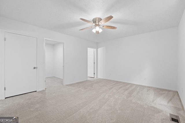 unfurnished bedroom with a textured ceiling, carpet flooring, visible vents, and baseboards