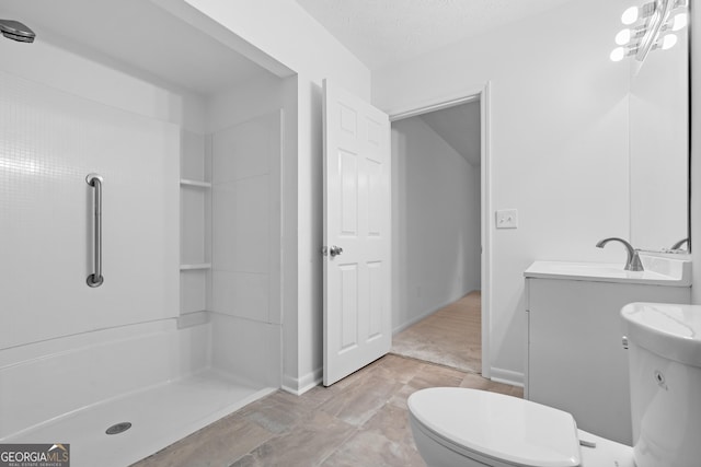 bathroom featuring baseboards, a shower, toilet, a textured ceiling, and vanity