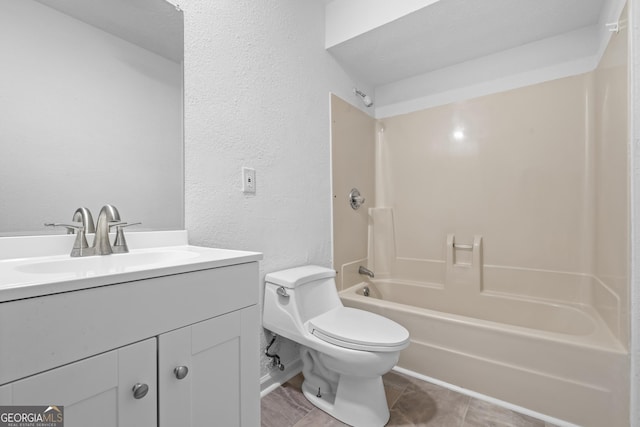 full bathroom featuring toilet, a textured wall, bathing tub / shower combination, and vanity