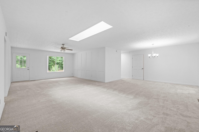 unfurnished room with light carpet, a skylight, a textured ceiling, and ceiling fan with notable chandelier