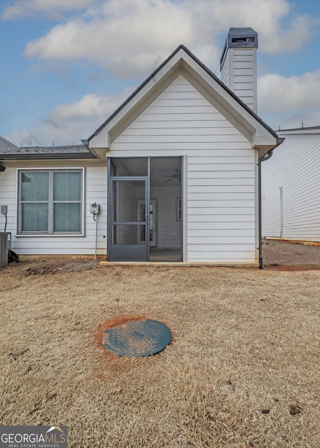 rear view of property with a chimney and a sunroom