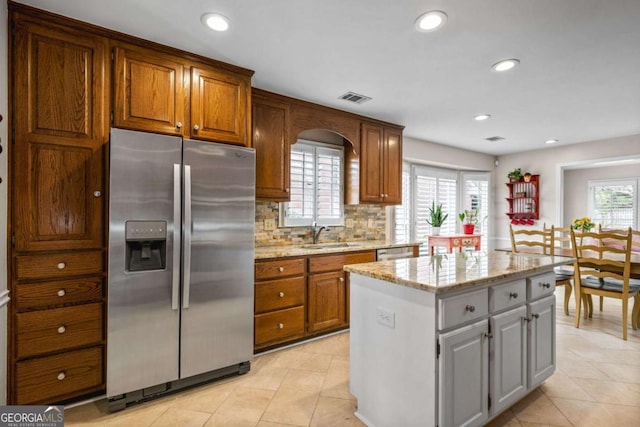 kitchen with tasteful backsplash, visible vents, a center island, stainless steel appliances, and a sink