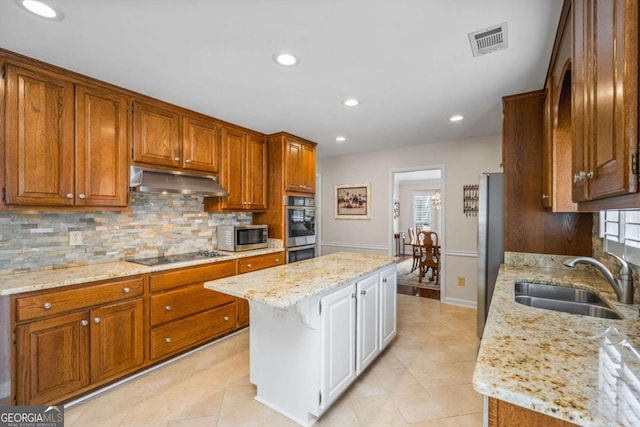 kitchen with under cabinet range hood, a sink, visible vents, appliances with stainless steel finishes, and backsplash