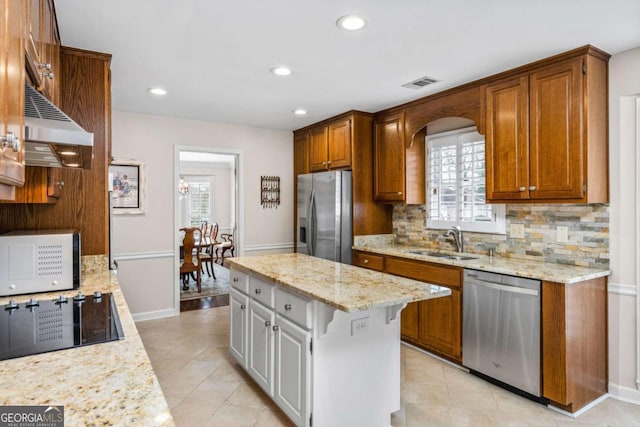 kitchen with light stone counters, stainless steel appliances, recessed lighting, backsplash, and a sink