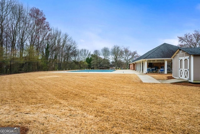 view of yard featuring an outdoor pool, a patio, a storage unit, fence, and an outdoor structure