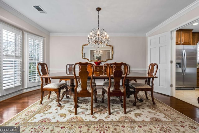 dining space with a chandelier, ornamental molding, light wood-type flooring, and visible vents