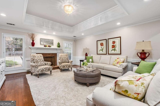 living room featuring a brick fireplace, visible vents, a raised ceiling, and a wealth of natural light