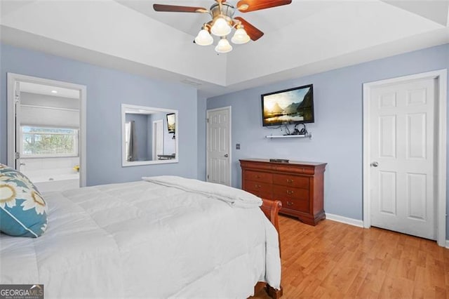 bedroom with a raised ceiling, baseboards, ceiling fan, and light wood finished floors