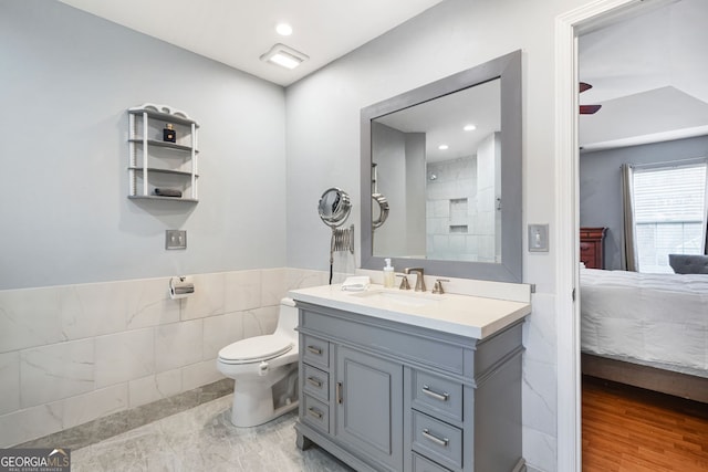 full bath with tile walls, recessed lighting, toilet, connected bathroom, and vanity