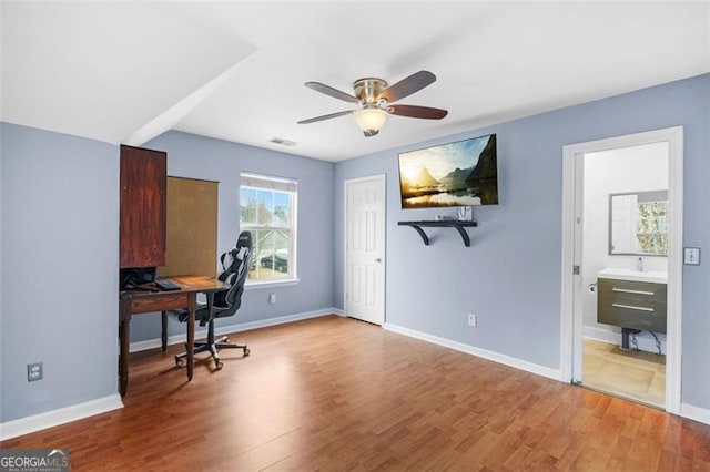 home office with a ceiling fan, visible vents, baseboards, and wood finished floors