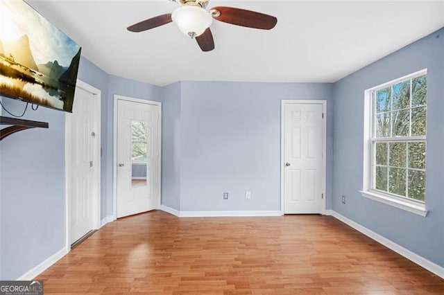 spare room with ceiling fan, light wood-style flooring, a wealth of natural light, and baseboards