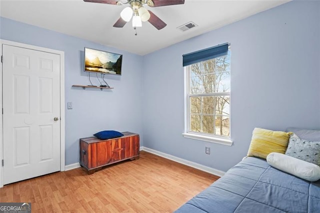 living area featuring light wood finished floors, baseboards, visible vents, and a ceiling fan