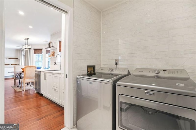 washroom featuring laundry area, ornamental molding, wood finished floors, independent washer and dryer, and a sink