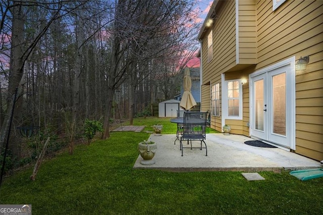 yard at dusk featuring an outbuilding, a patio area, and a shed