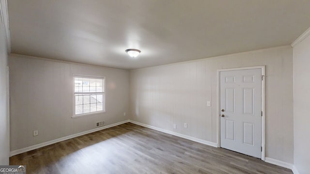 unfurnished room with visible vents, baseboards, and wood finished floors