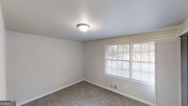 spare room featuring carpet, visible vents, and baseboards