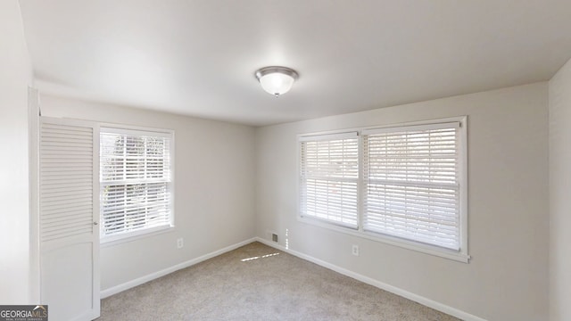 empty room with plenty of natural light, carpet flooring, and baseboards