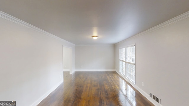 spare room featuring dark wood-style floors, visible vents, ornamental molding, and baseboards