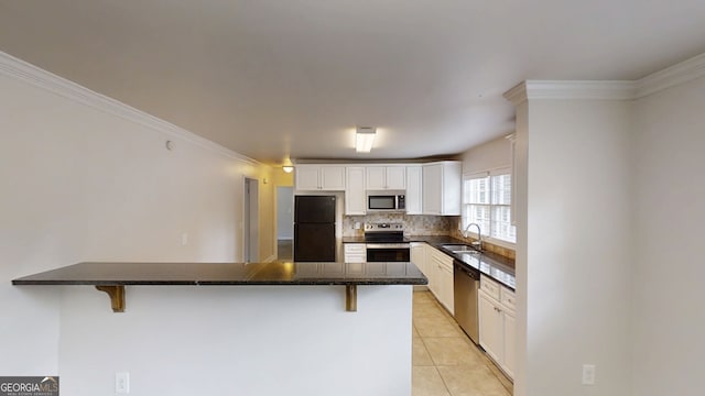 kitchen featuring light tile patterned floors, tasteful backsplash, appliances with stainless steel finishes, a kitchen breakfast bar, and white cabinetry