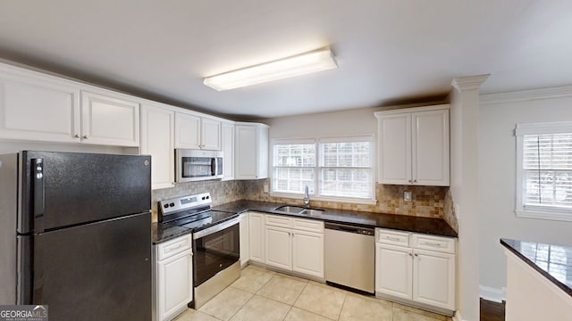 kitchen with tasteful backsplash, white cabinets, stainless steel appliances, a sink, and light tile patterned flooring