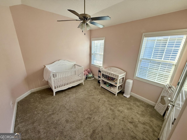 bedroom featuring carpet, vaulted ceiling, a crib, and baseboards