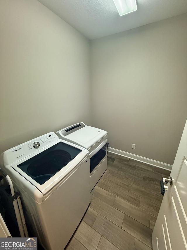 laundry room with washing machine and dryer, laundry area, wood finish floors, and baseboards