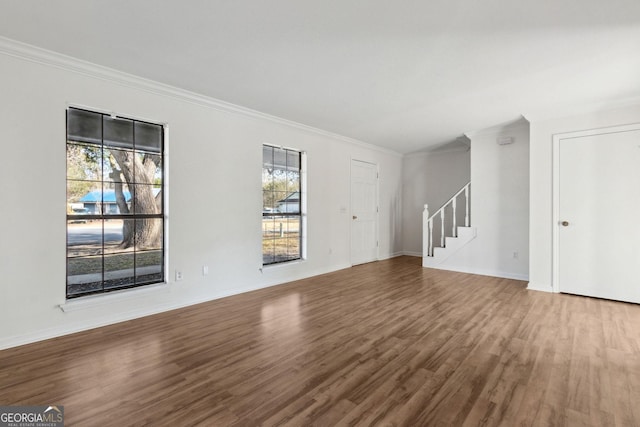 unfurnished living room with baseboards, stairway, wood finished floors, and crown molding