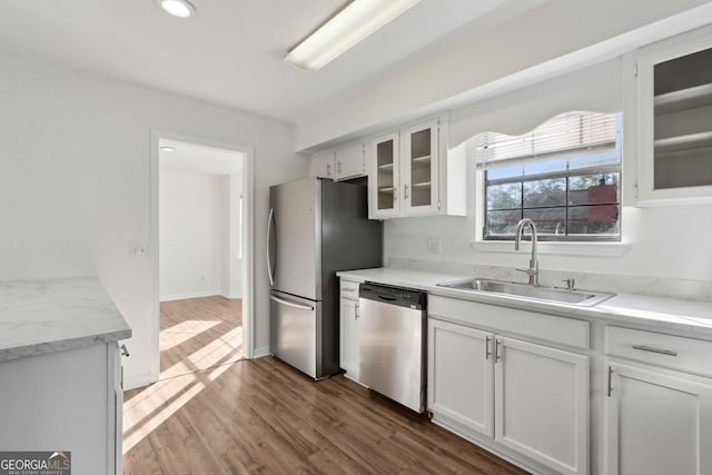 kitchen featuring white cabinets, glass insert cabinets, appliances with stainless steel finishes, wood finished floors, and a sink