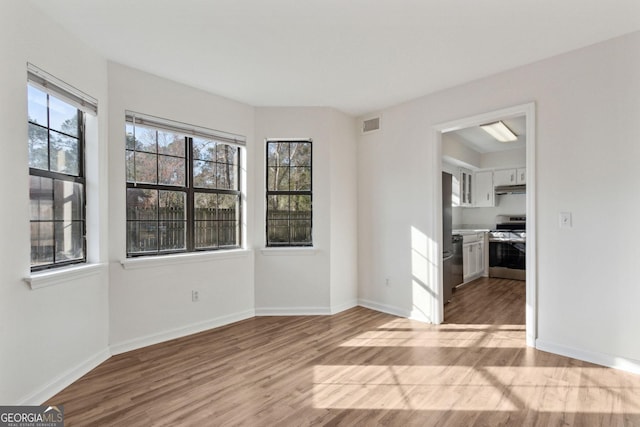 unfurnished room with a healthy amount of sunlight, light wood-style flooring, and baseboards