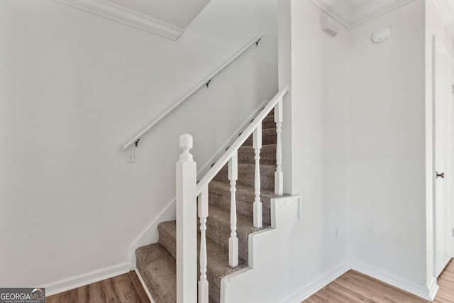 stairs with crown molding, baseboards, and wood finished floors