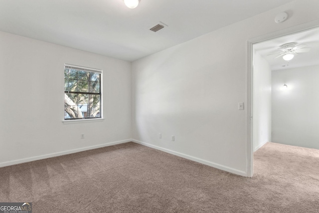 carpeted spare room with visible vents, ceiling fan, and baseboards