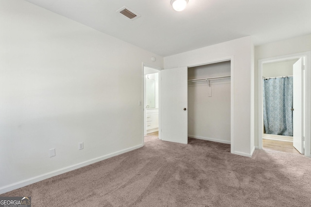 unfurnished bedroom featuring visible vents, baseboards, ensuite bath, carpet floors, and a closet